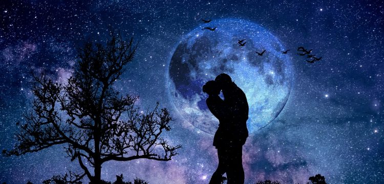 Silhouetted couple embracing at night in front of the moon.