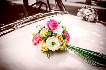 Wedding bouquet atop an old car.