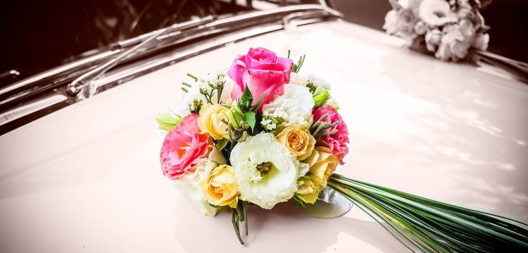 Wedding bouquet atop an old car.