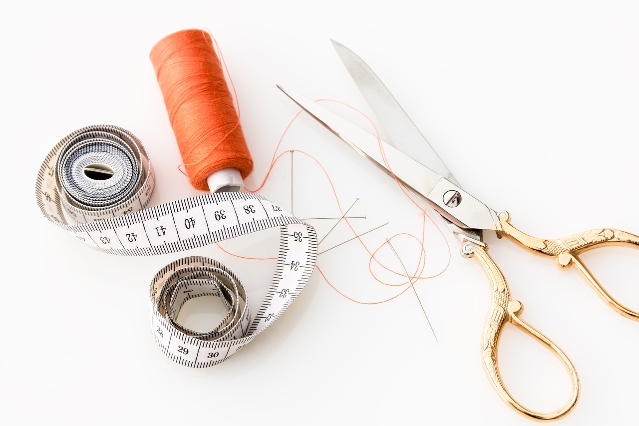 Measuring tape with scissors and spool of thread.