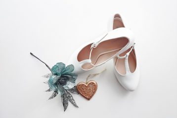 A pair of bridal shoes and a flower.