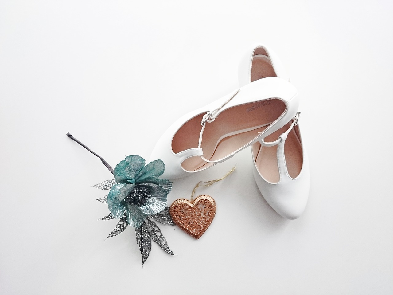 A pair of bridal shoes and a flower.