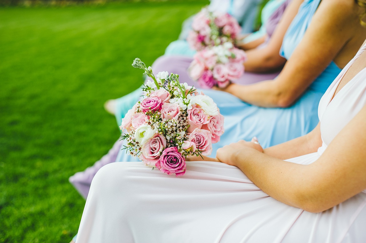 A row of bridesmaids sitting with a bride and with flower bouquets.