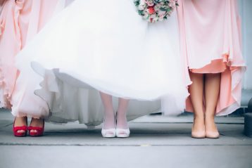 A bride standing with her bridesmaids, shown from the waist down.