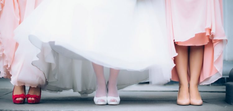 A bride standing with her bridesmaids, shown from the waist down.