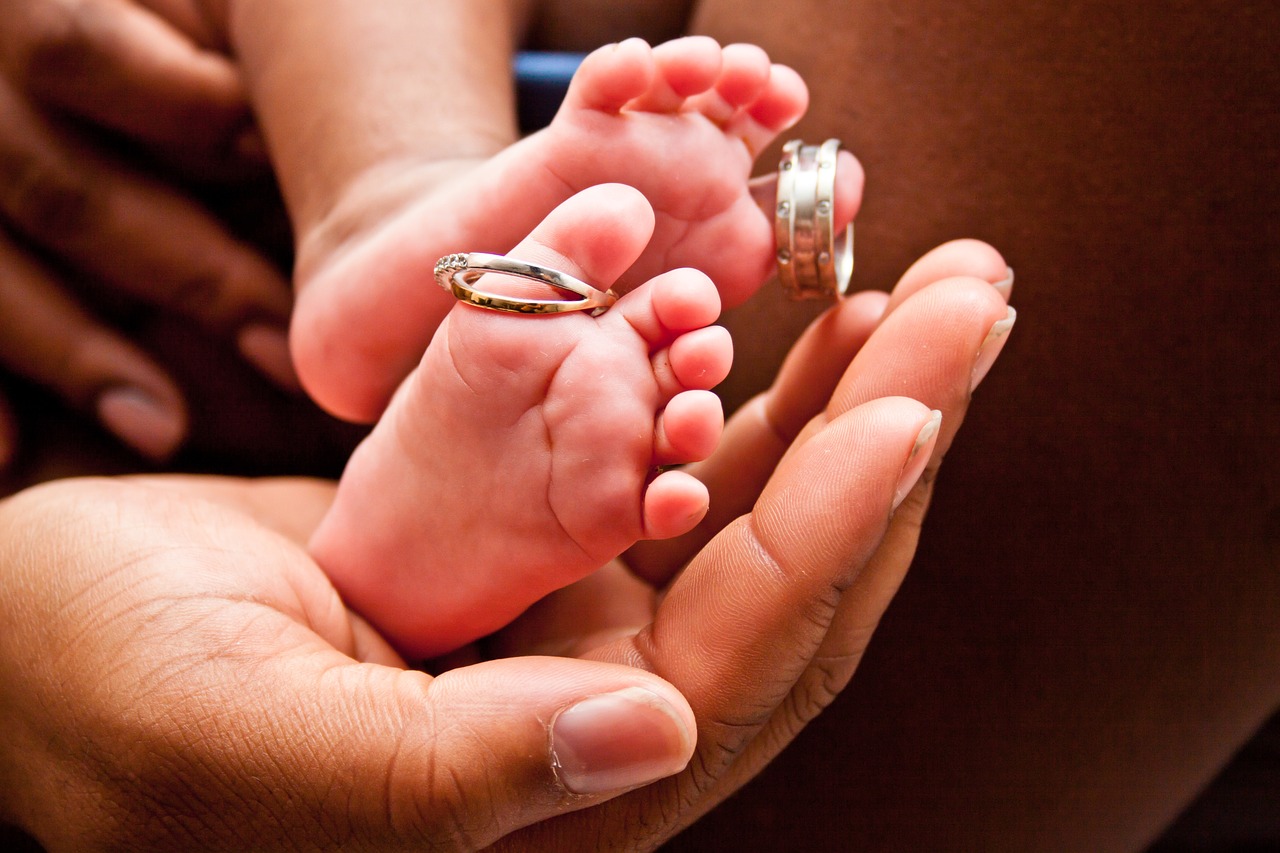 Newborn baby's feet with wedding rings on the toes.