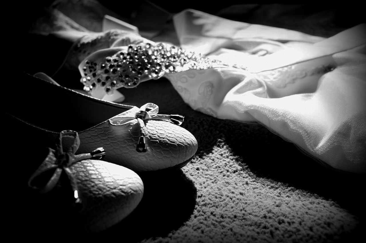Black and white photo of a wedding dress and shoes.