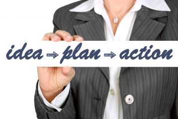 A businesswoman holding a sign reading "idea, plan, action".