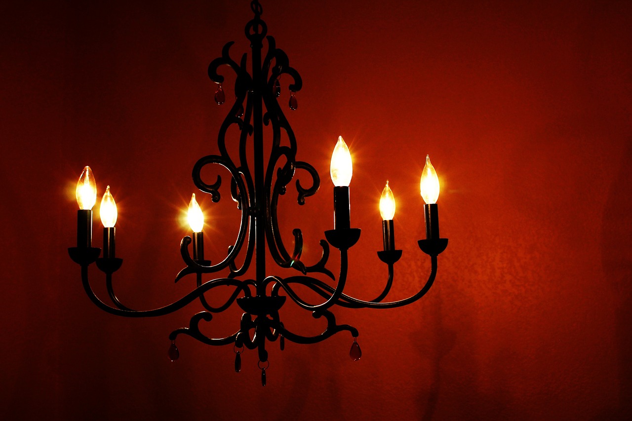 Goth inspired chandelier in front of a deep red wall.