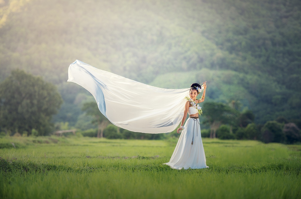 Bride in field with her veil flying in the wind.