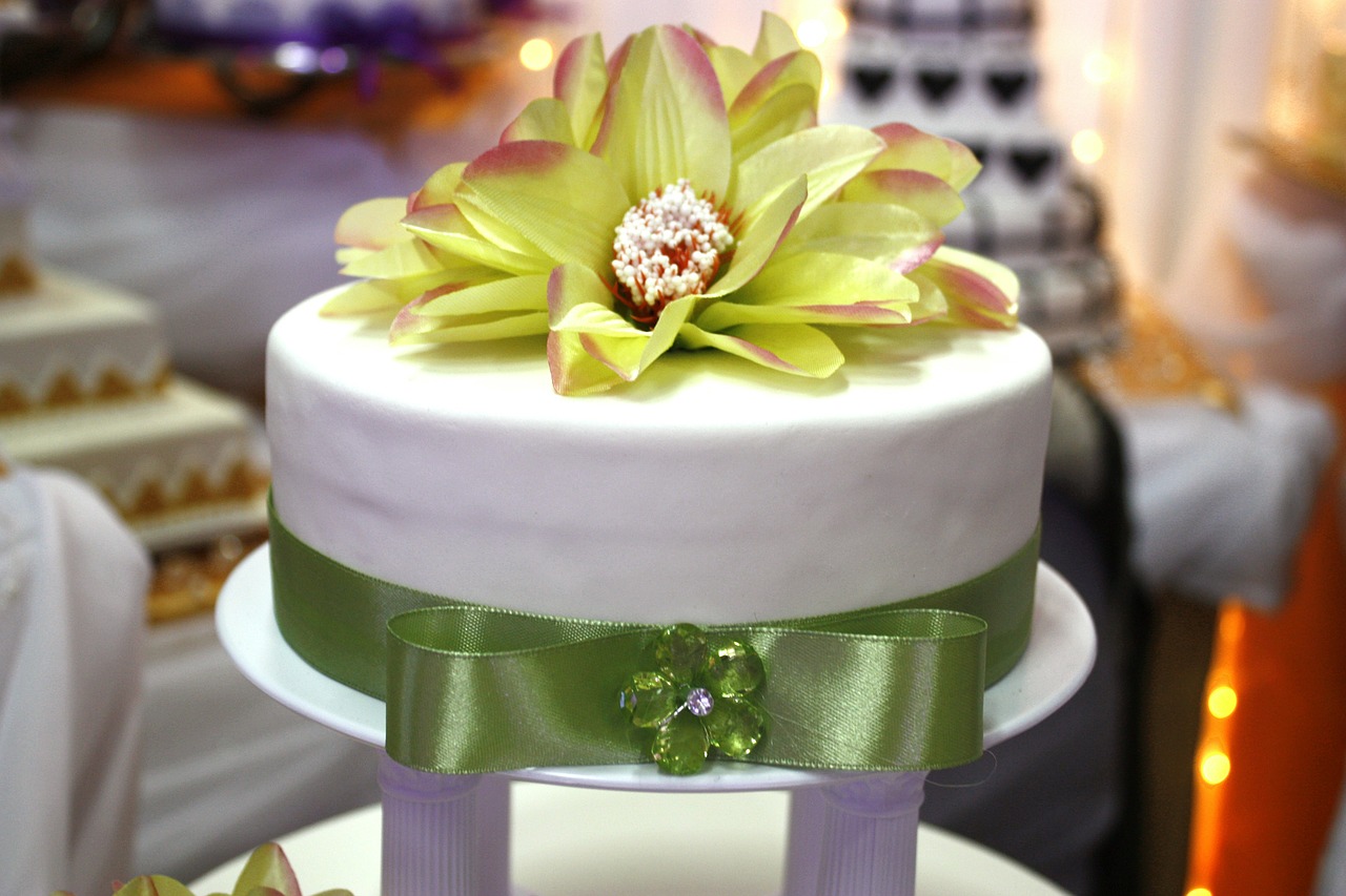 A green and white wedding cake with a large flower on top.