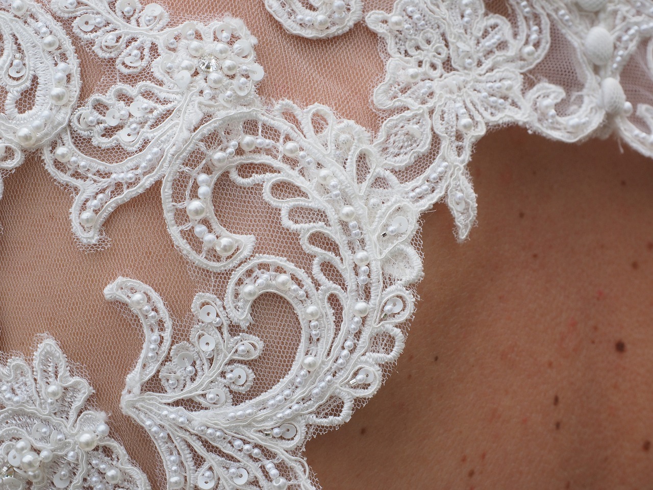 Close up of bridal gown material on a bride's shoulder.