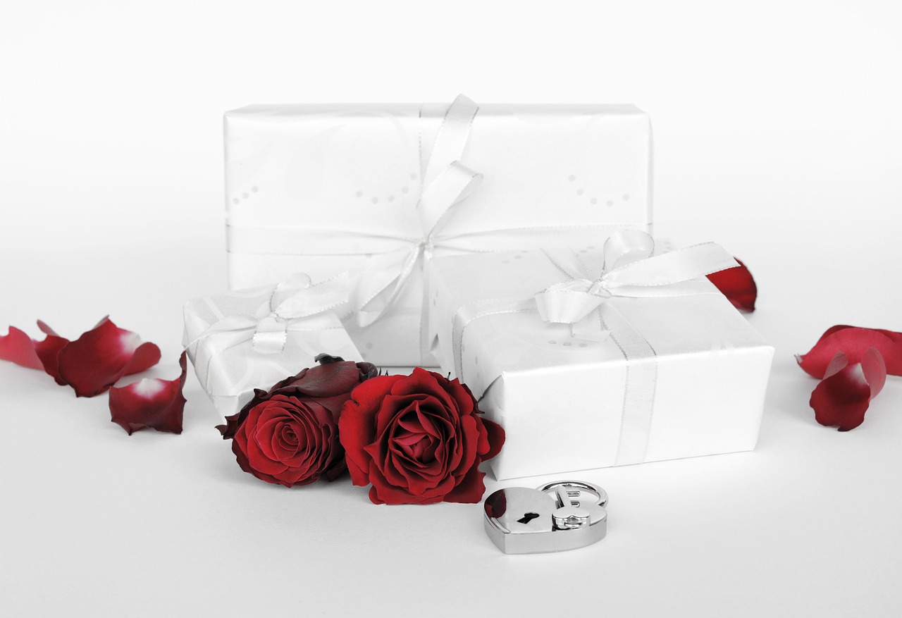 Wedding gifts sitting next to red roses.