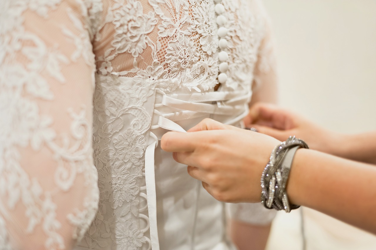 Someone tying the corset on a lacy wedding gown.