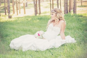 Bride with a bouquet lying on the grass.