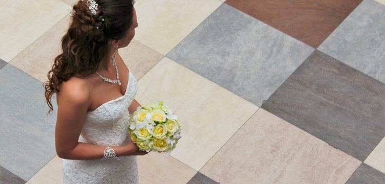 A bride holding a yellow bouquet, looking over her shoulder.