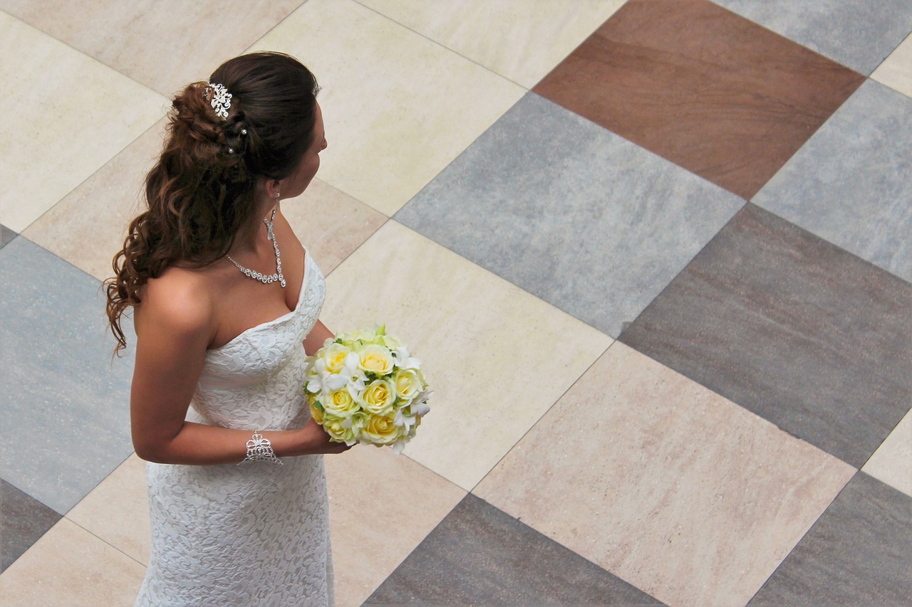 A bride holding a yellow bouquet, looking over her shoulder.