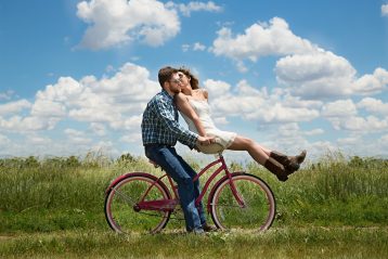 Engaged couple riding a bicycle.