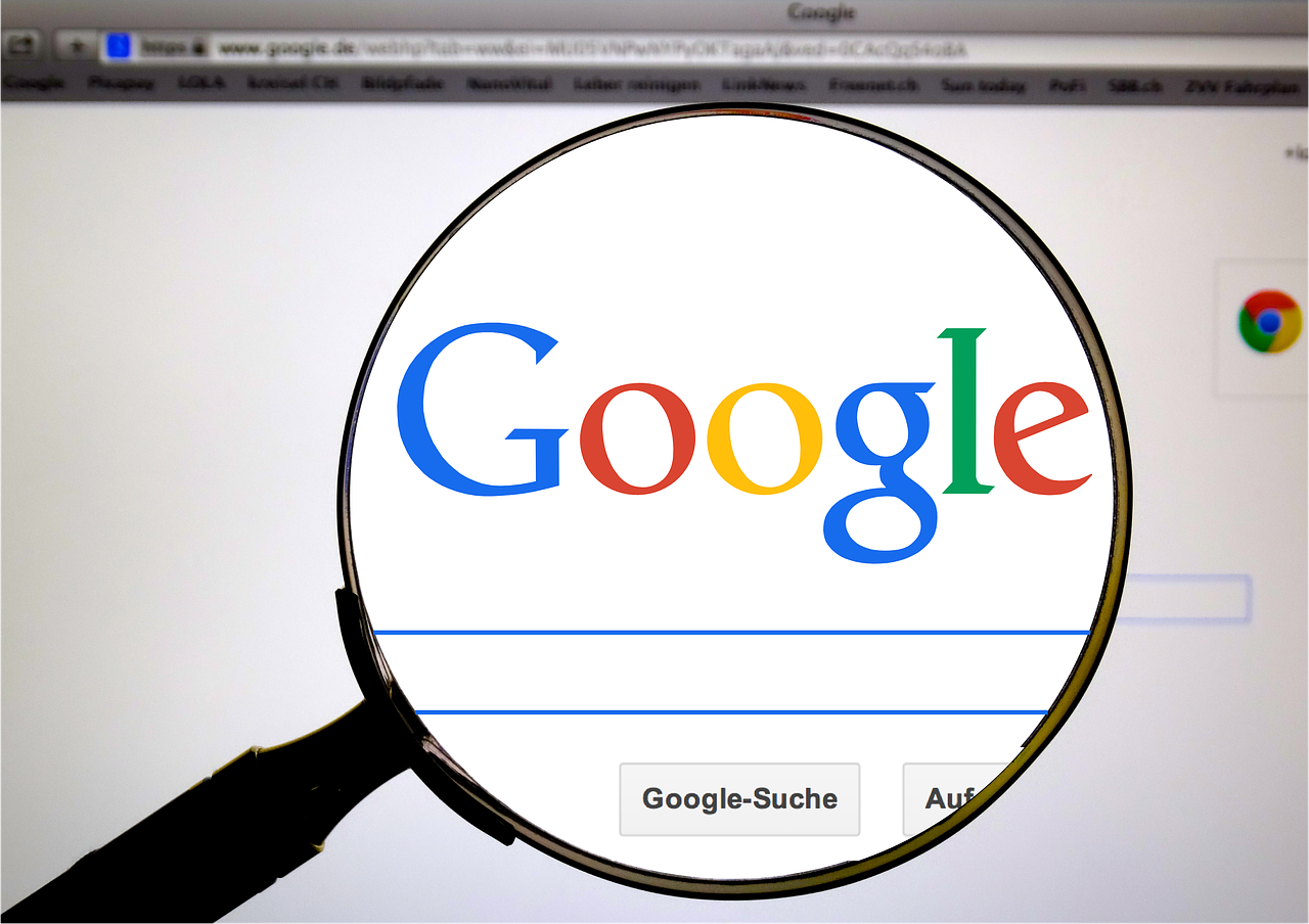 A magnifying glass focusing on the Google logo on a computer screen.