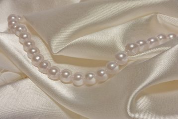 Silk material with a strand of pearls lying on it.