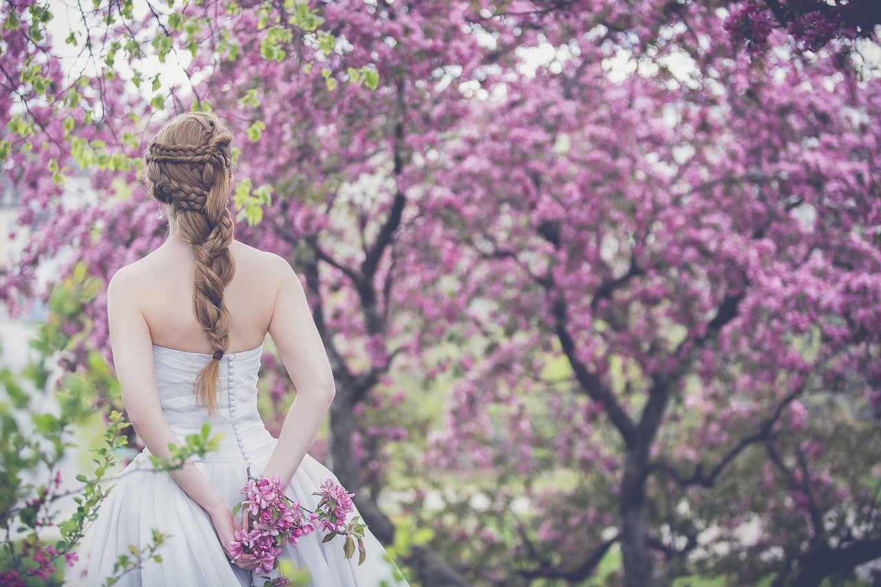 A bride walking through a grove of purple colored trees.