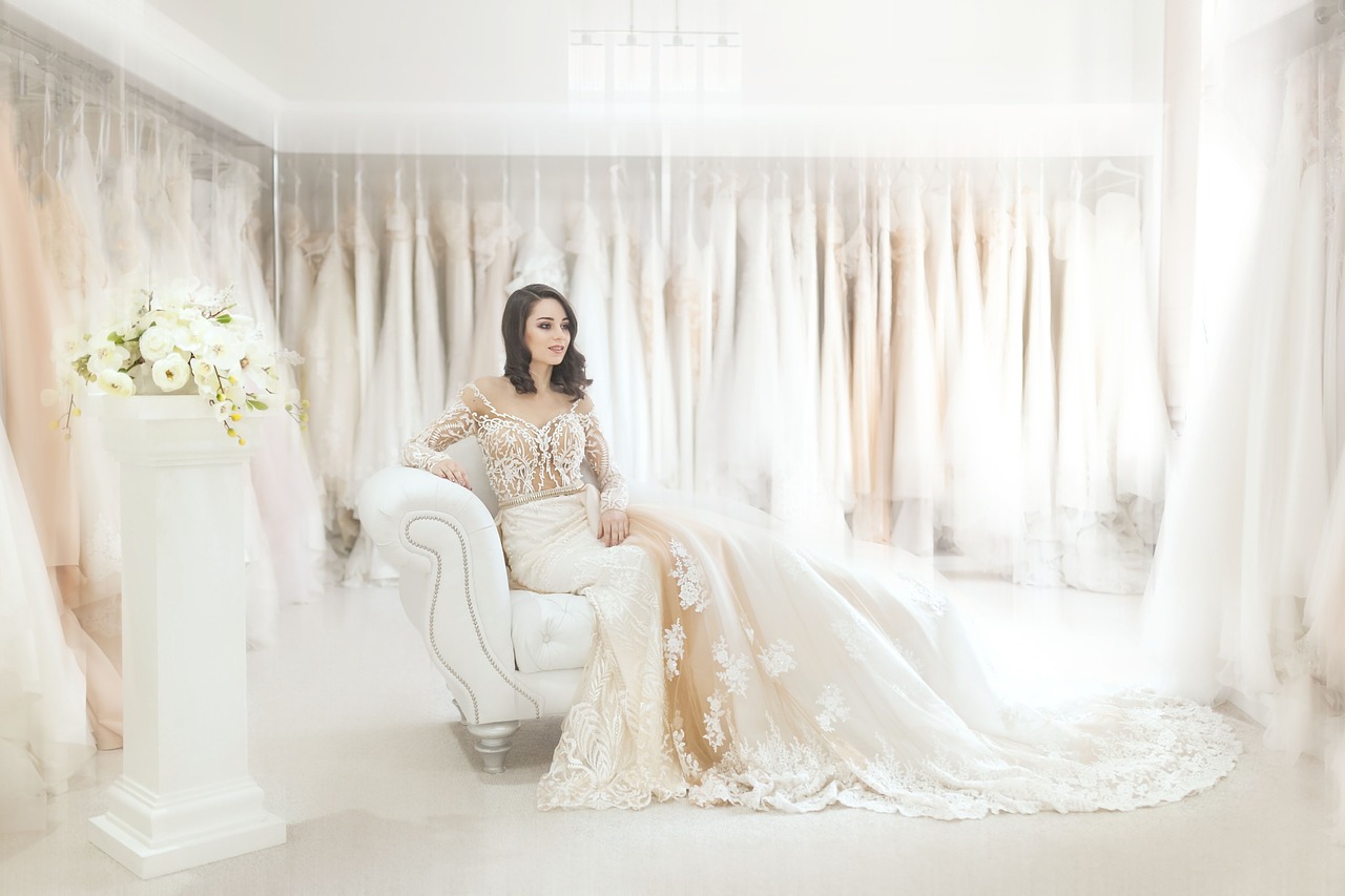 Bride in a dress sitting on a chair in an all white room.