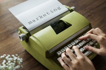 A typewriter with a paper in it with the word "marketing" typed on it.