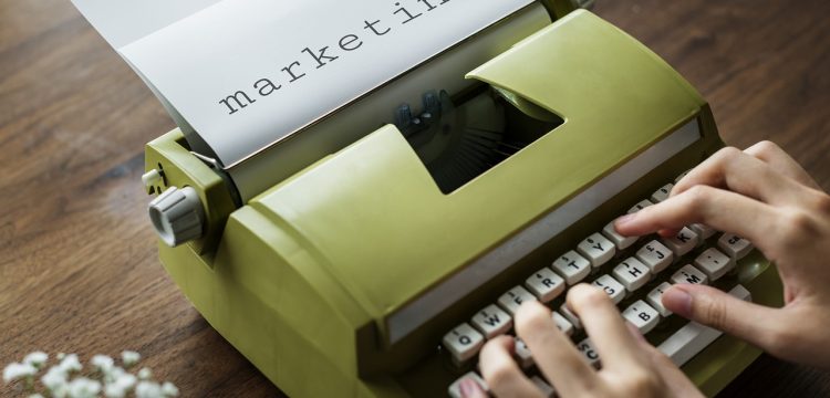 A typewriter with a paper in it with the word "marketing" typed on it.