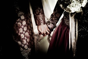 A medieval couple holding hands in their wedding finery.