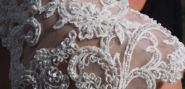 An intricately beaded lace shoulder of a bridal gown.