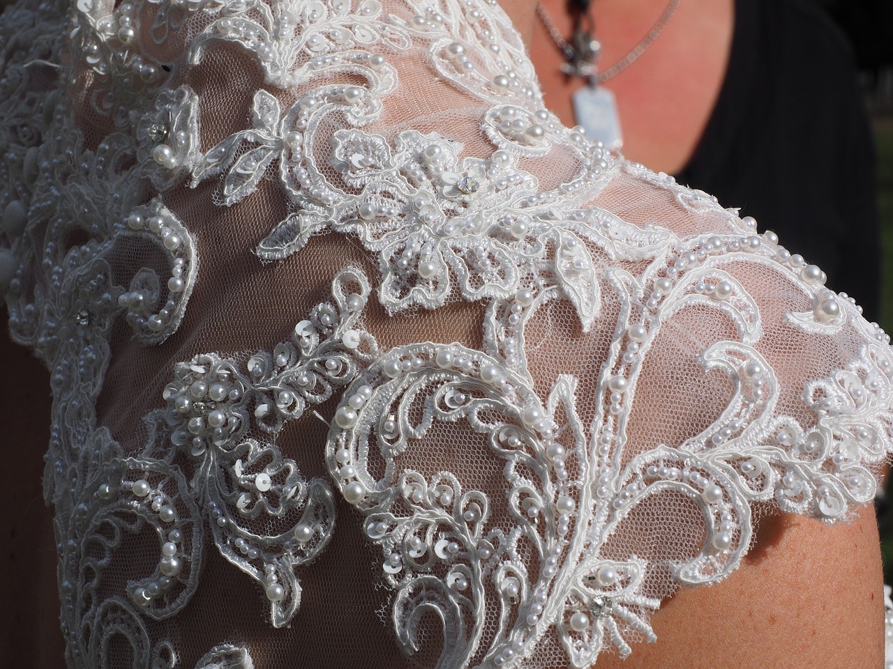 An intricately beaded lace shoulder of a bridal gown.