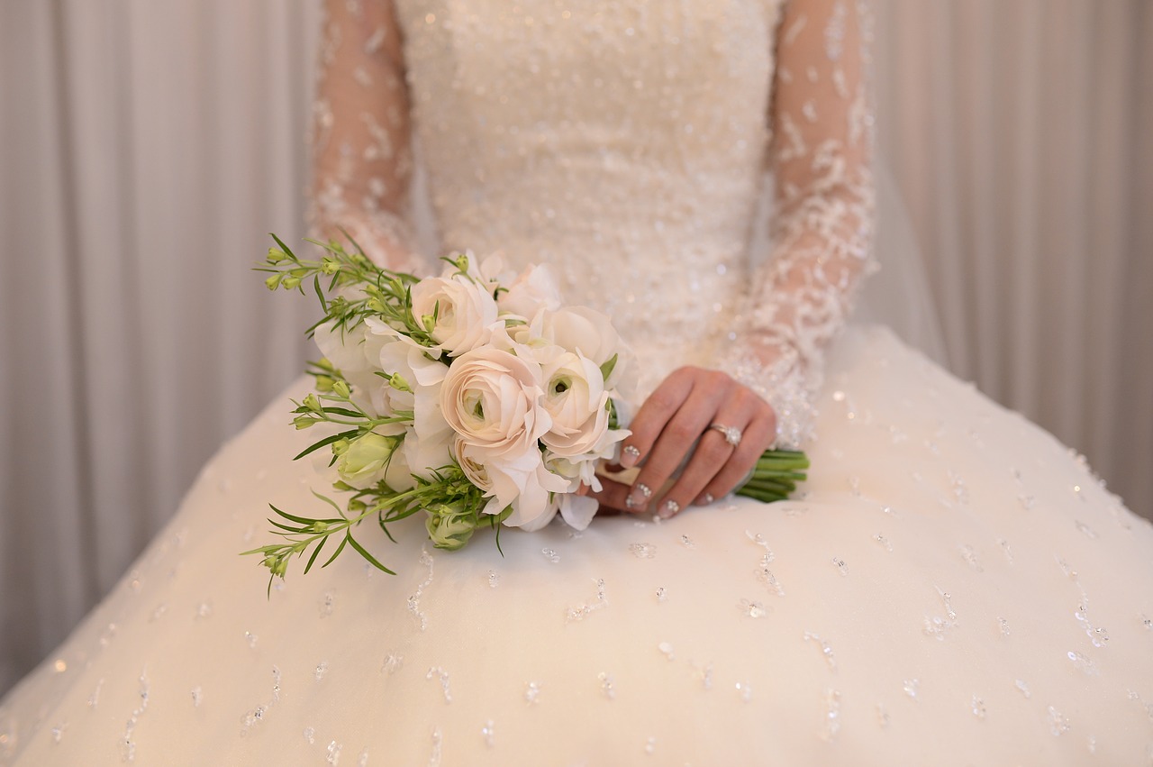 A torso view of a bride wearing a long sleeved wedding gown.