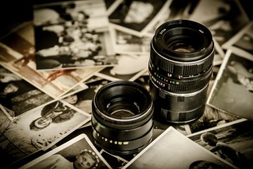Two camera lenses surrounded by photographs.