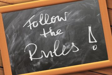 A blackboard that reads, "Follow the Rules".