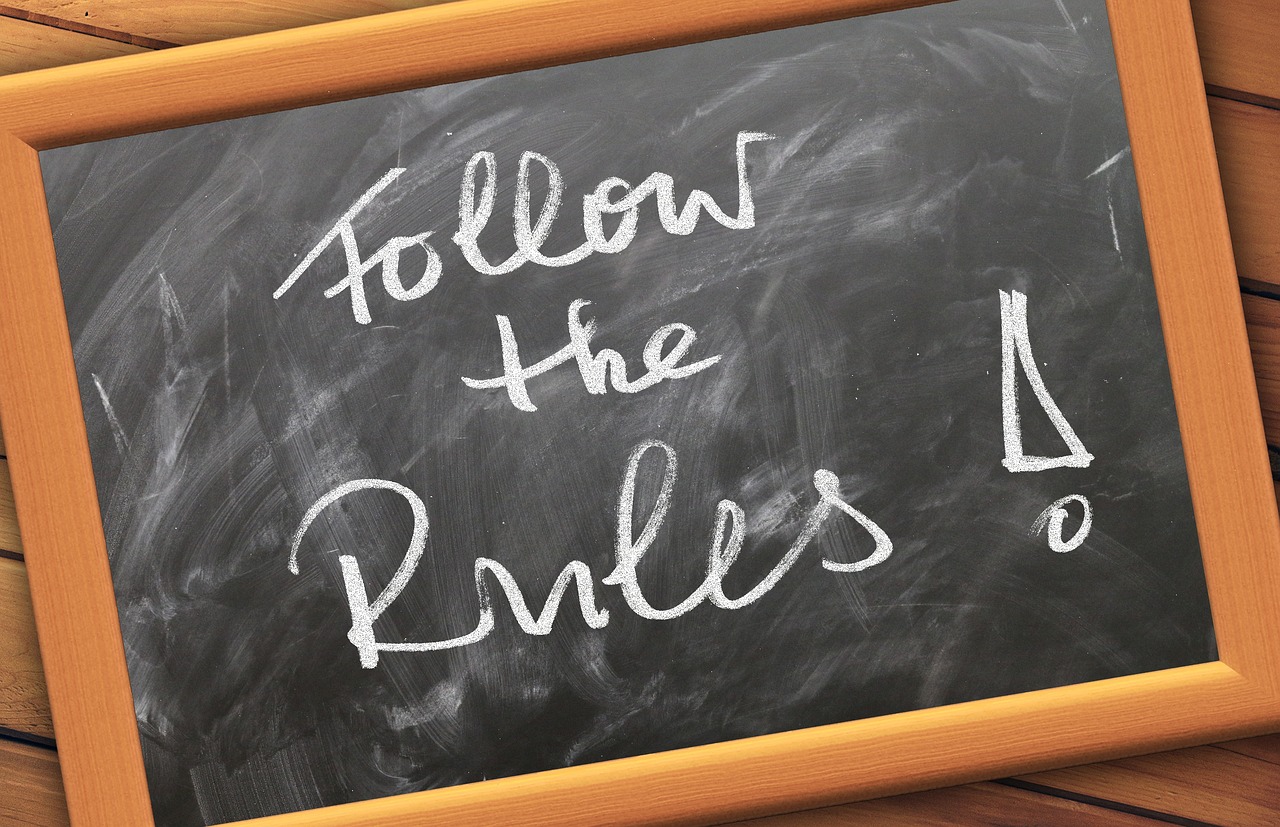A blackboard that reads, "Follow the Rules".