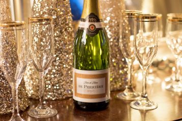 A bottle of champagne with champagne flutes and glittery decorations.