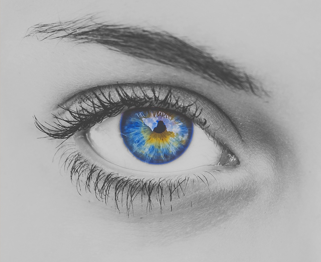 A black and white photo of a woman's eye with the pupil multi-colored.
