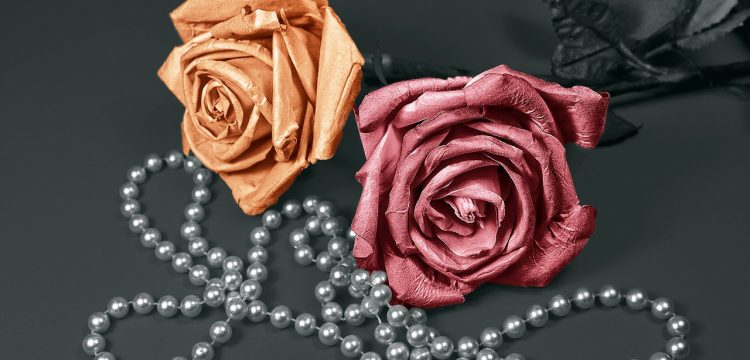 Two roses with a strand of pearls.