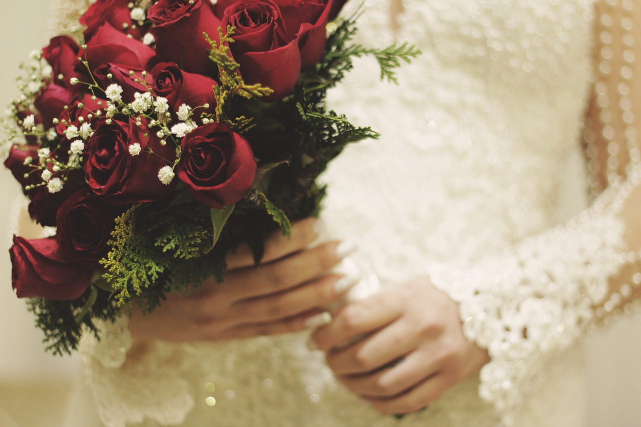 Torso shot of a bride holding red roses and baby's breath.