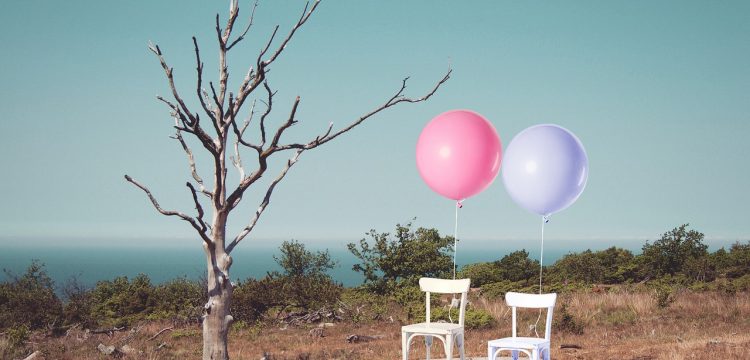 Pink and purple balloons tied to white chairs.