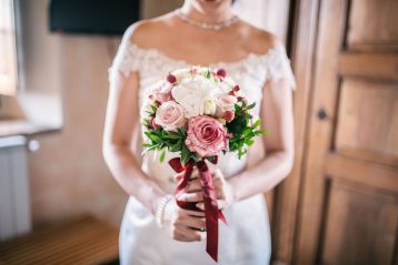 Bride holding a red, white, and pink bouquet.