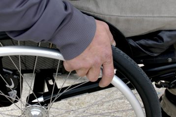 Close up of man grabbing wheelchair wheel.