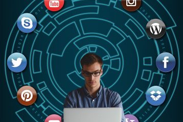 Man sitting at a laptop with various social media icons surrounding him.
