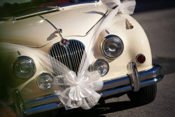 A luxury car with a white ribbon and bow made of tulle draped on it.