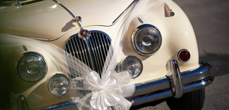 A luxury car with a white ribbon and bow made of tulle draped on it.