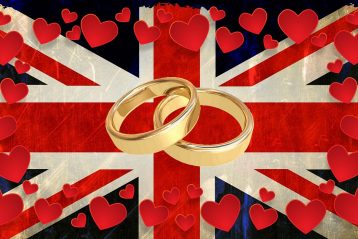 Wedding bands surrounded by hearts and lying on a British flag.