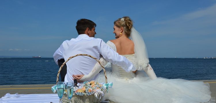 Bride and groom on beach with glasses of champagne.