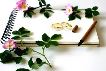 Wedding rings with flowers around it.