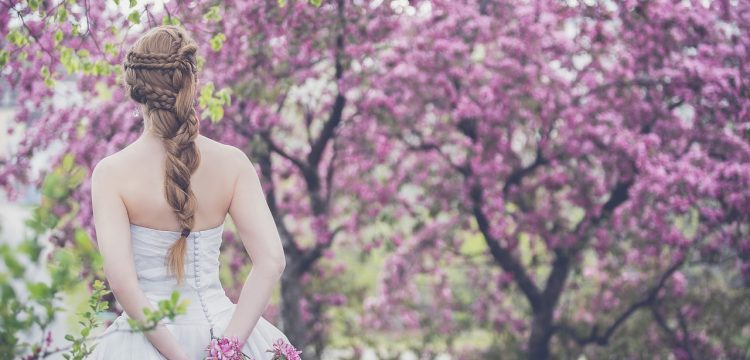 Bride standing among flowering trees.