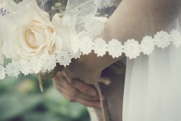 A bride standing with white roses.